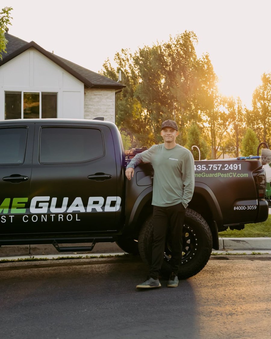 HomeGuard owner standing beside the wrapped HomeGuard Pest Control truck at sunset