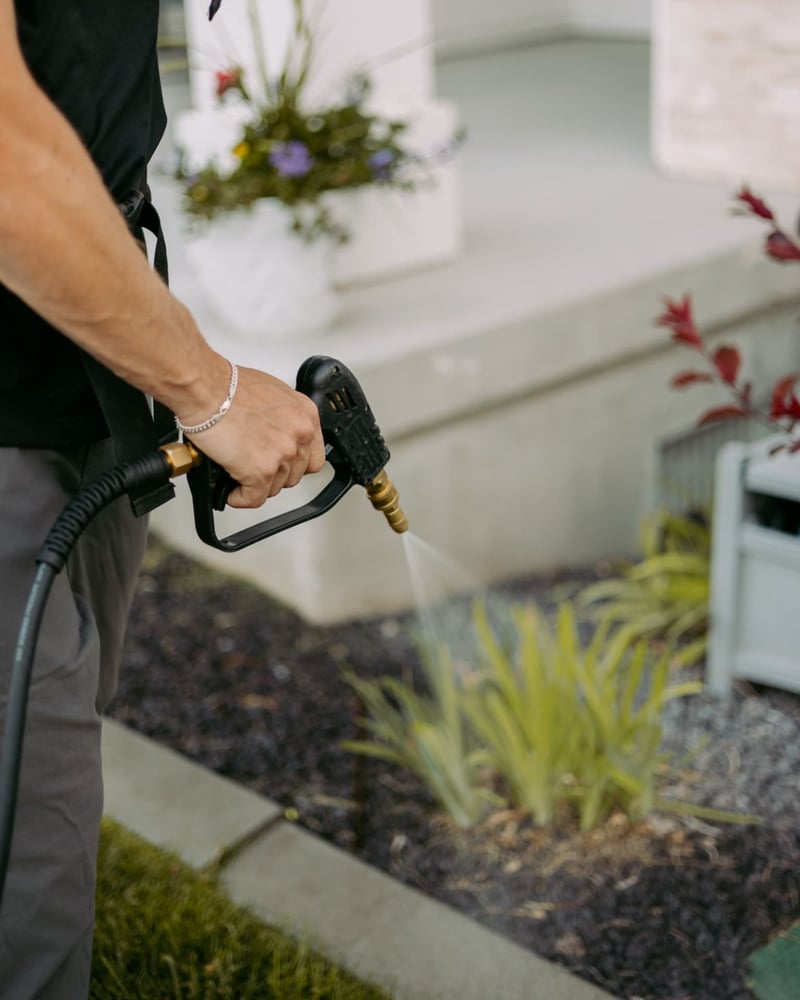 Close-up of a HomeGuard spray nozzle treating a landscape bed